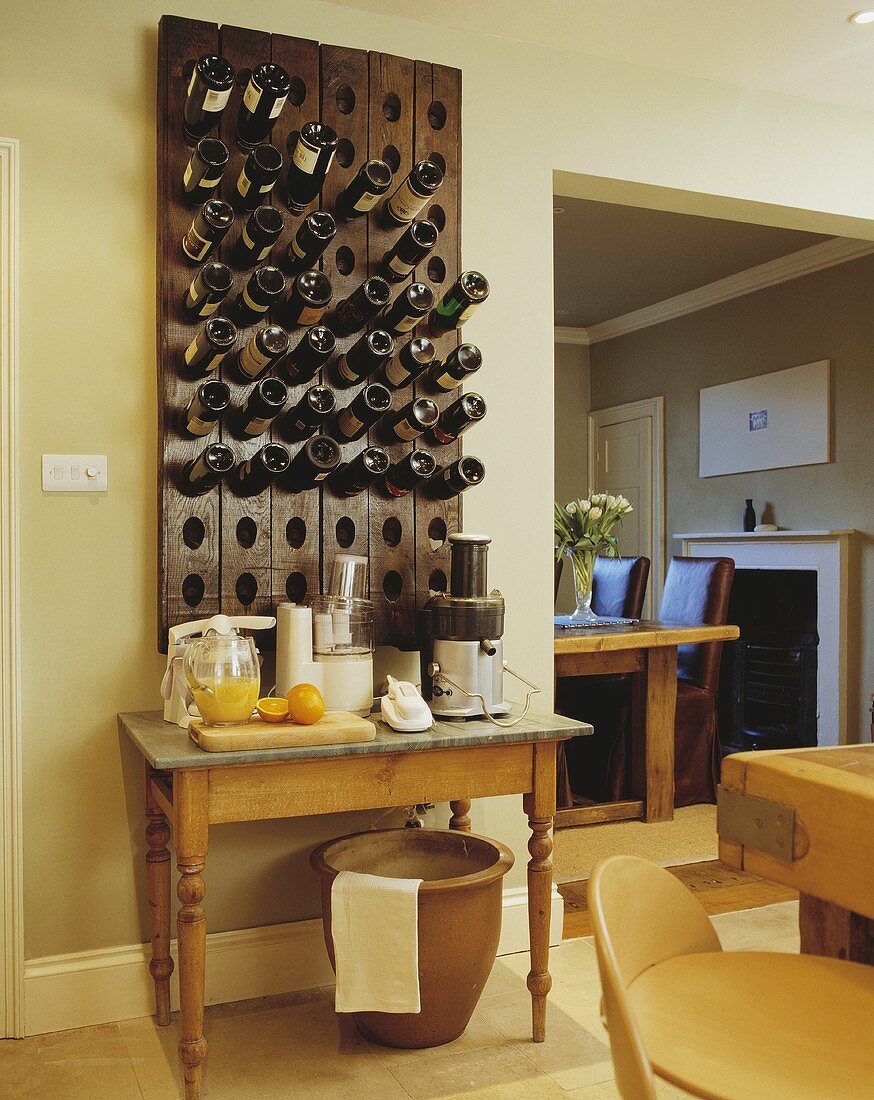 Rustikale Weinlagerung mit Flaschen in Holzpanel über ländlichem Tisch an getönter Wand