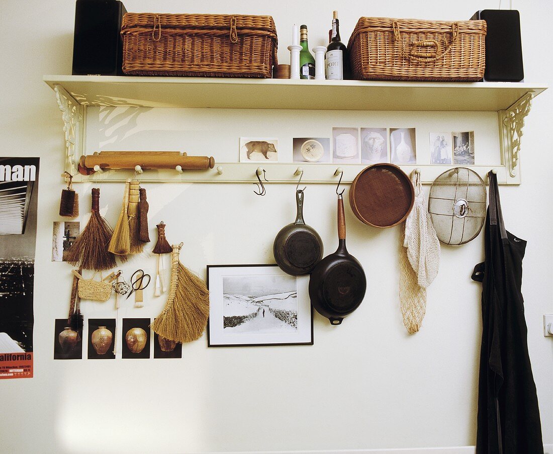 Küchenboard mit gehängten Pfannen und Korbtruhen auf Regal