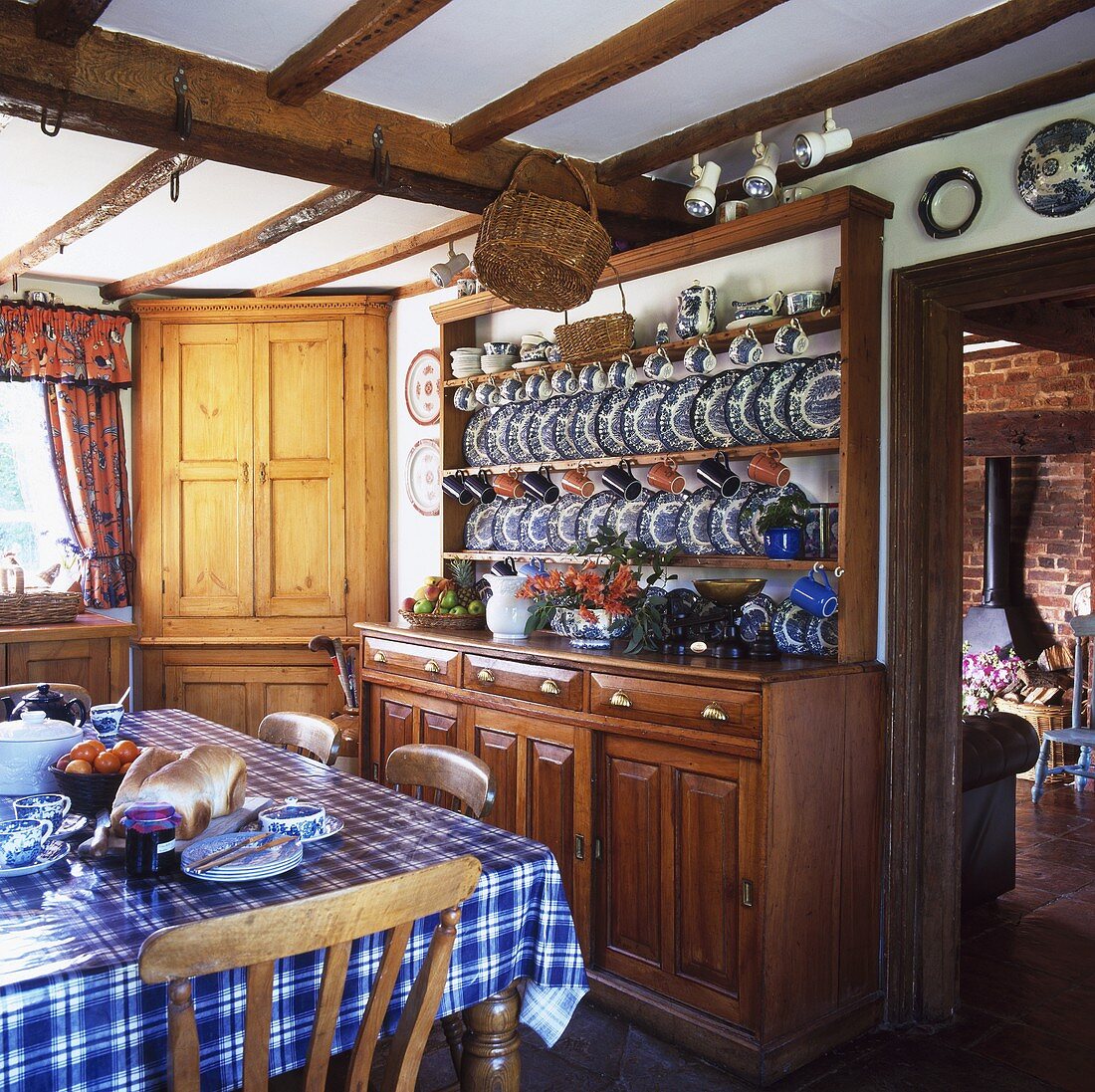 Landhausküche mit kariertem Tischtuch auf dem Esstisch und Geschirrschrank mit weiss blauen Tellern