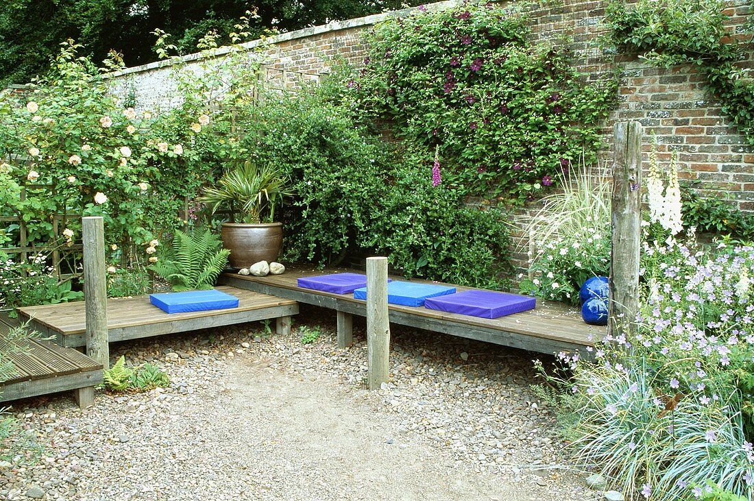 Holzbänke mit blauen Polstern im Garten