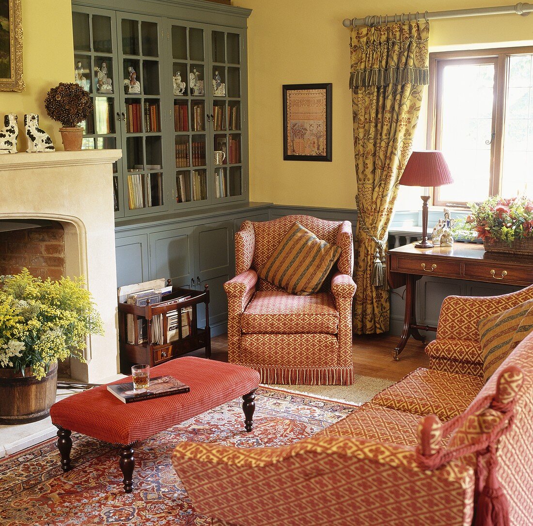 Gemusterte roten Sofagarnitur im Wohnzimmer mit hellgelben Wänden und grau-blauem Einbauschrank