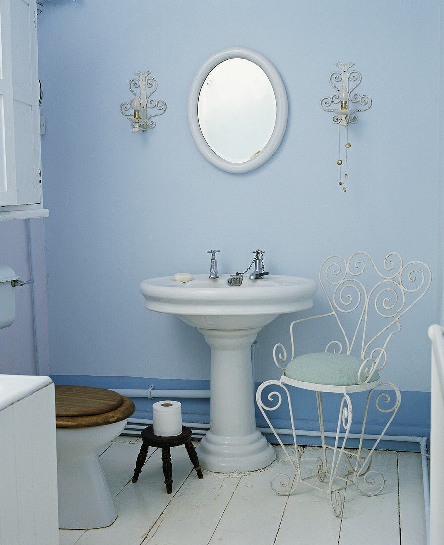 Traditionelles blaues Badezimmer mit Standwaschbecken und Stuhl aus weißem Metall