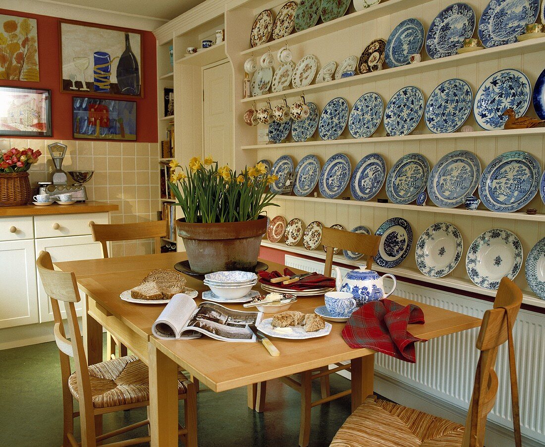 Esstisch mit Frühstück vor Wandregal mit blau weißen Tellern