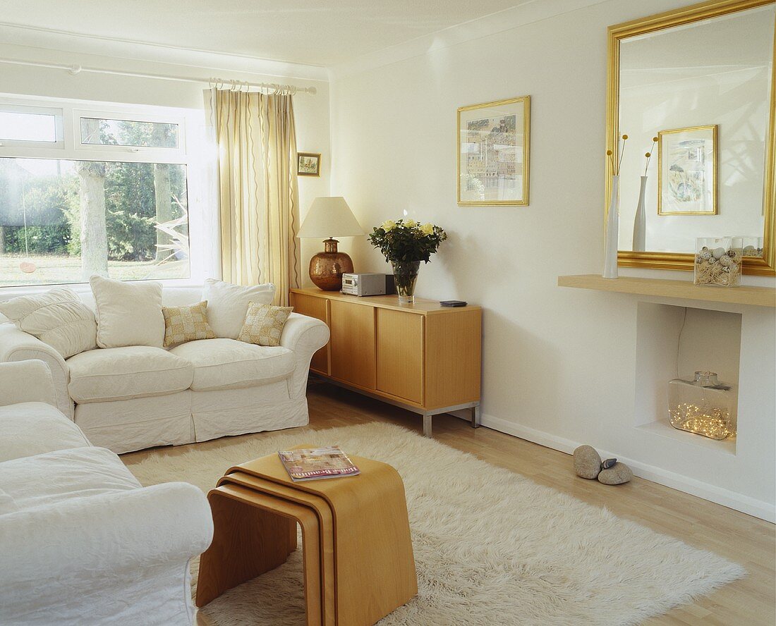 weiße Sofagarnitur und mehrteiliges Beistelltischset im Wohnzimmer