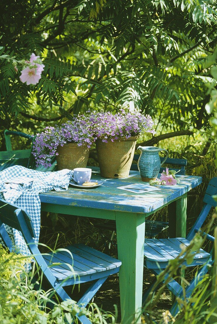 Pflanzentöpfe auf grün und blau lackiertem Gartentisch
