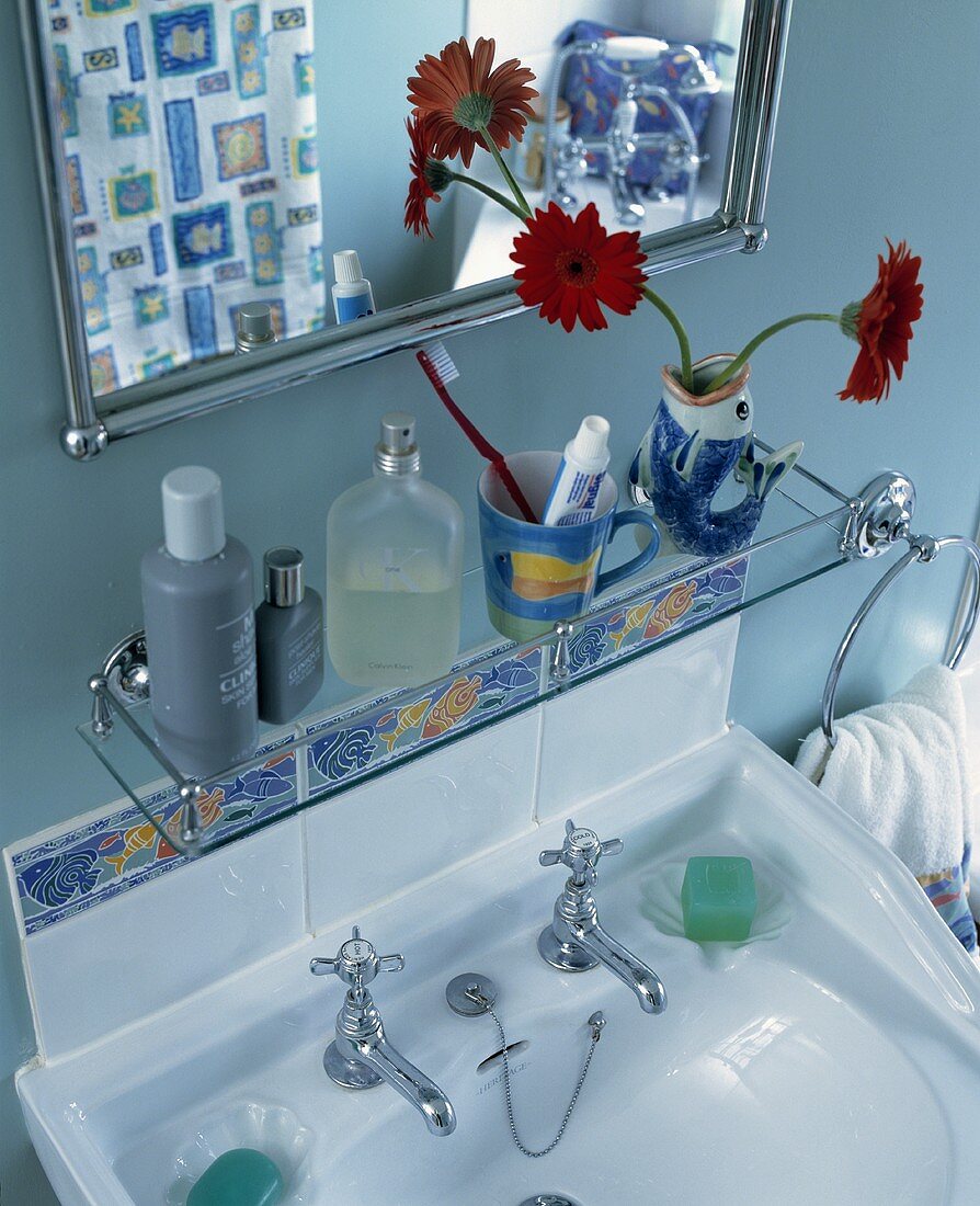 Glasablage und Spiegel über weißes Waschbecken vor blauer Wand