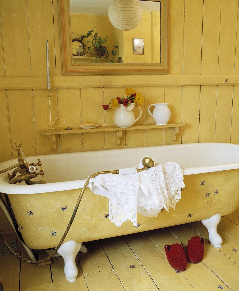 Gelbe freistehende Badewanne im Vintagelook vor gelber Holzwand