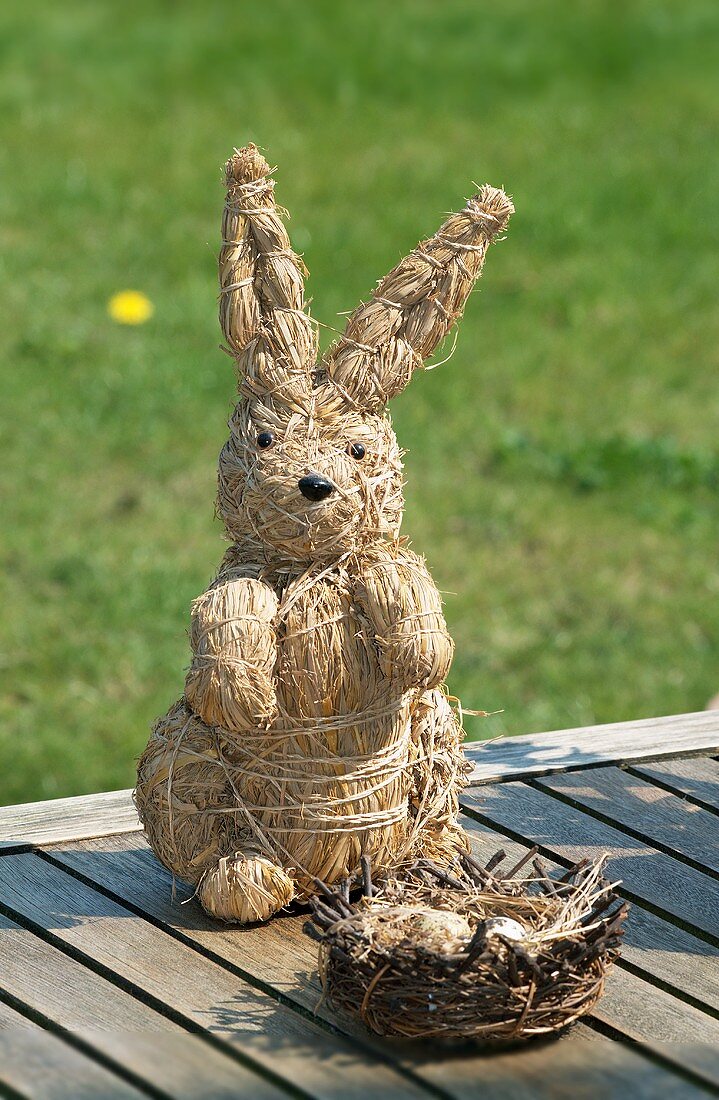 A straw rabbit figure with a nest on wooden boards