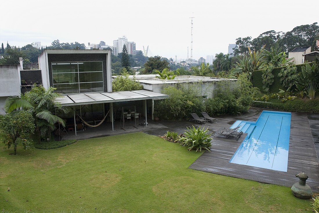 A garden of a newly built house with a pool and a glass facade