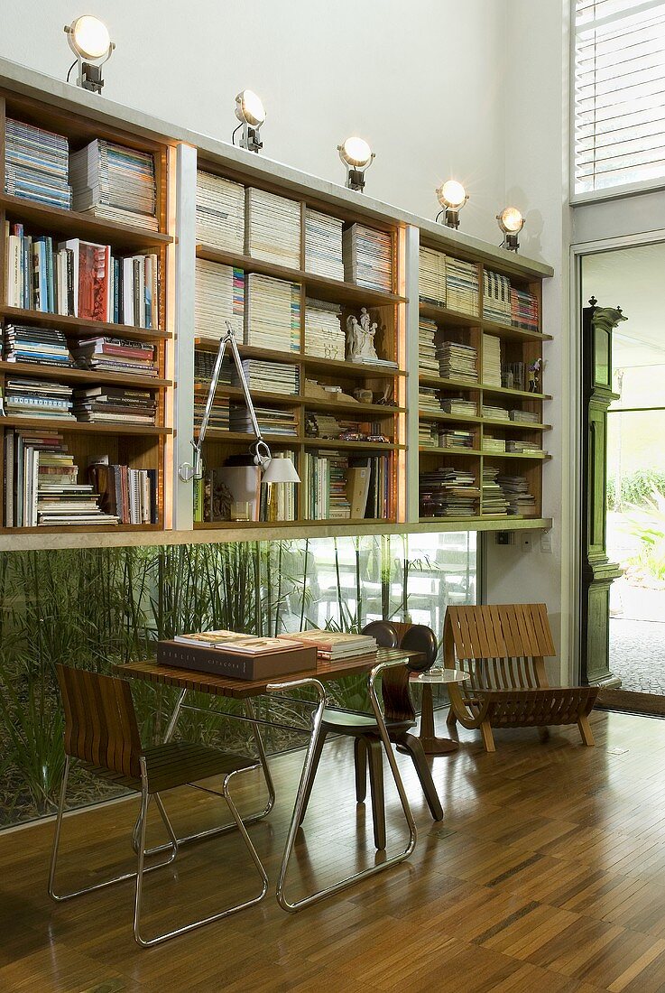 Arbeitsecke mit Tisch und Stuhl im Stilmix vor Bücherregal über Fenster im Bodenbereich