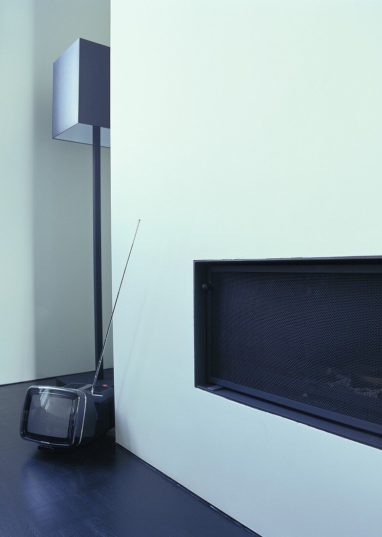 A built-in fireplace, a floor lamp by Jen Alkema and a mini television on the floor