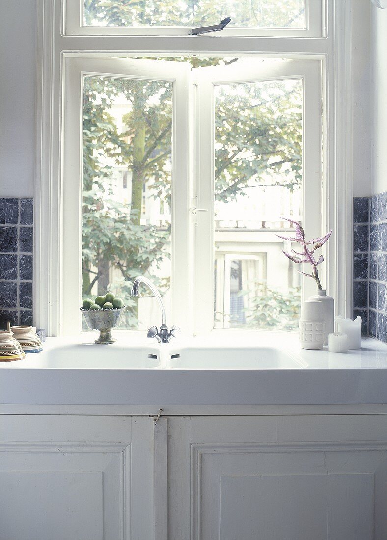 Antikes Spülbecken aus Porzellan mit weißem Unterschrank unter dem Fenster