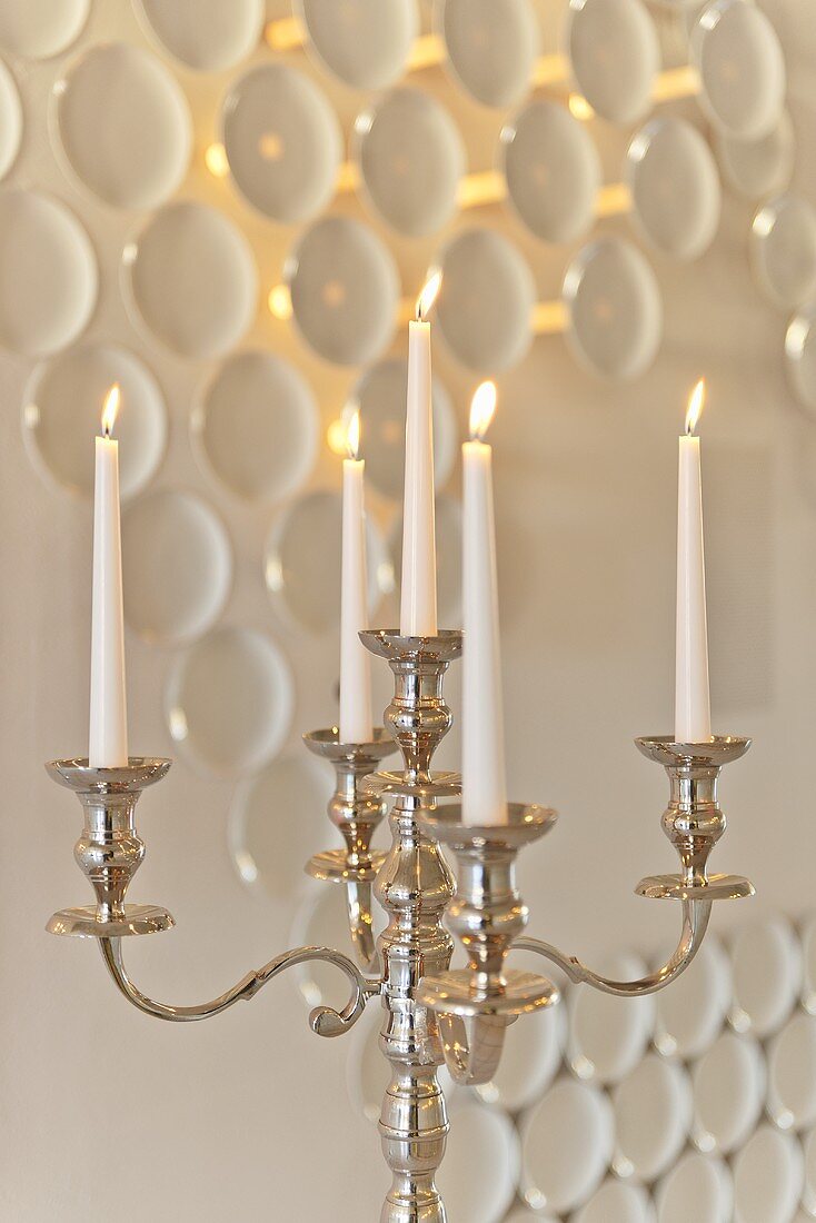 Burning candles in a candle holder against a wall decoration with porcelain, Rosenthal Casino, Selb