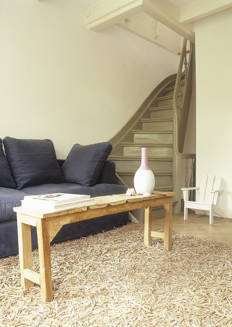 A living room with a sofa, a wooden floor and a rug