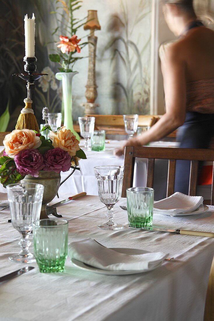 Gedeckter Tisch mit grünen Gläser, Blumen und Kerze