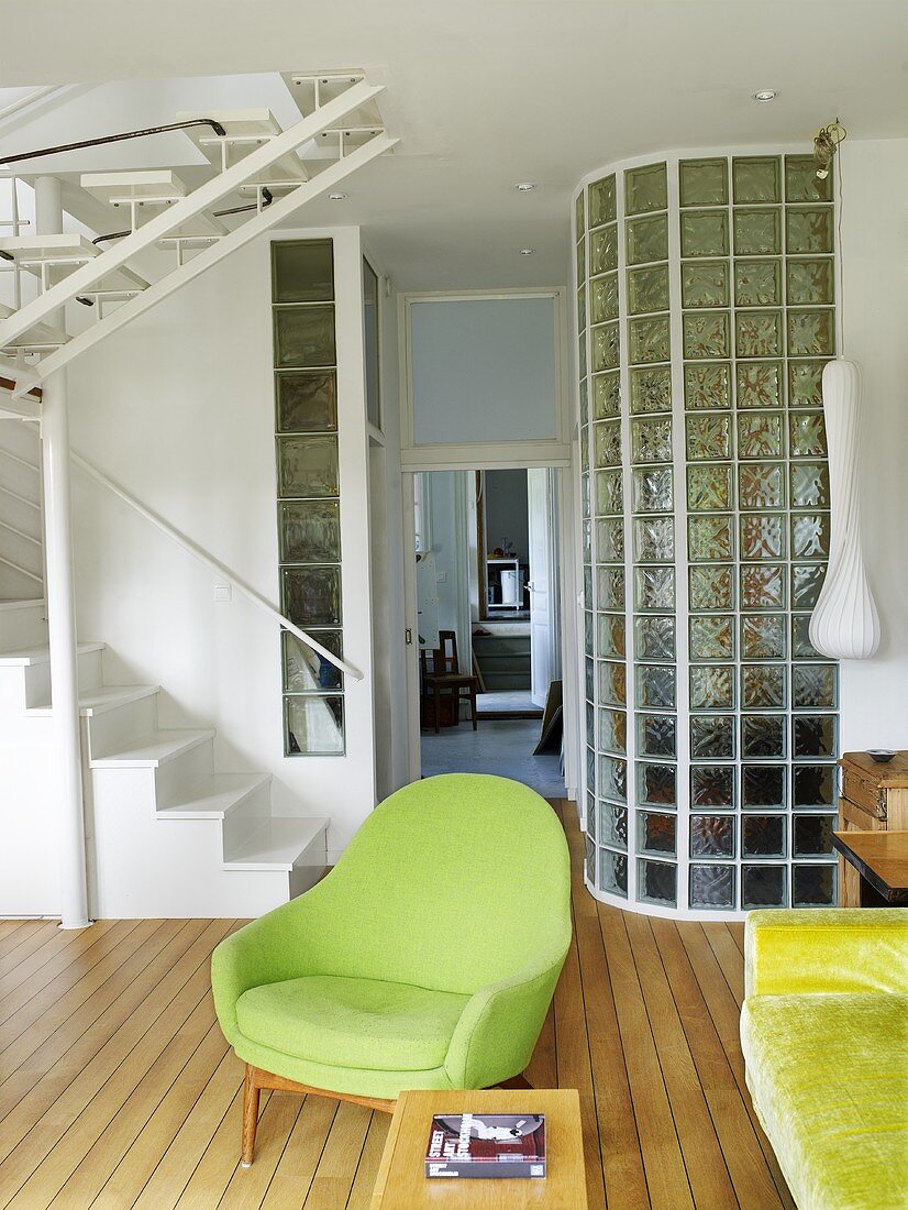 A green armchair next to a flight of stairs in a living room