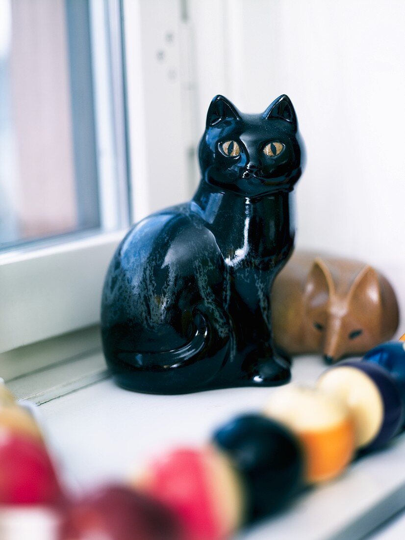 A cat ornament on a window sill