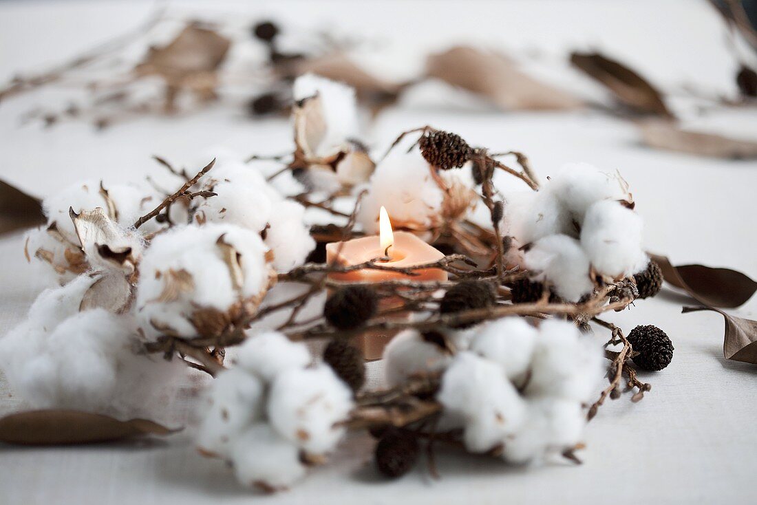 A wintry wreath made of cotton, cones and a candle