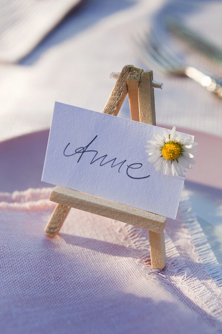 A place card with the name 'Anne' on a mini easel with a daisy