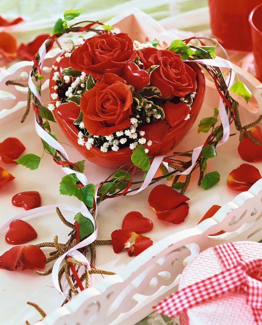 Red roses and gypsophila in red heart-shaped bowl