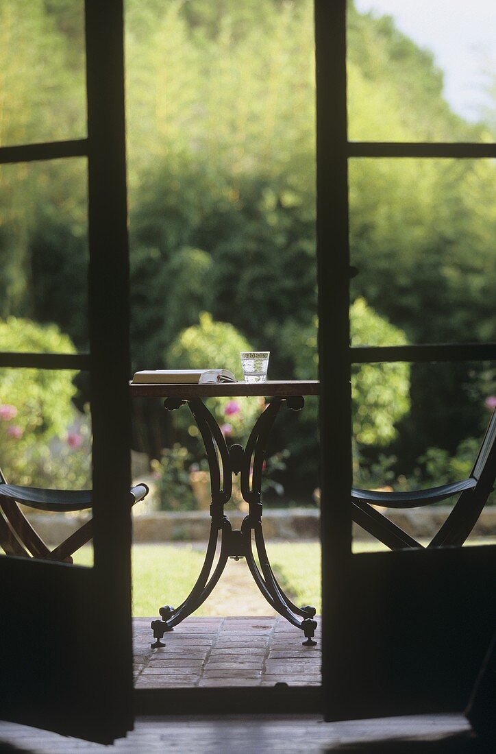 Glas Wasser und ein Buch auf Gartentisch