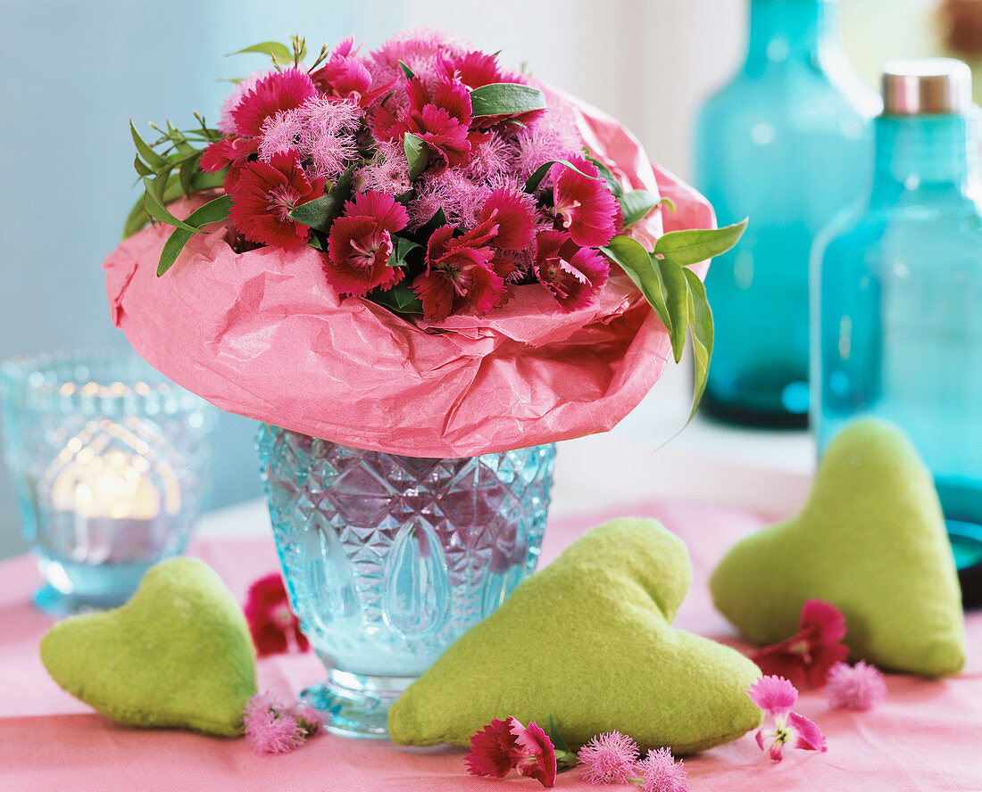 Bouquet of pinks with pink paper frill in blue glass vase