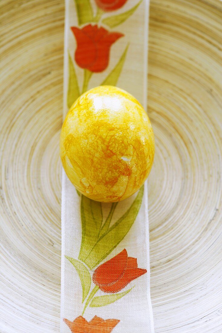 A yellow Easter egg on printed ribbon