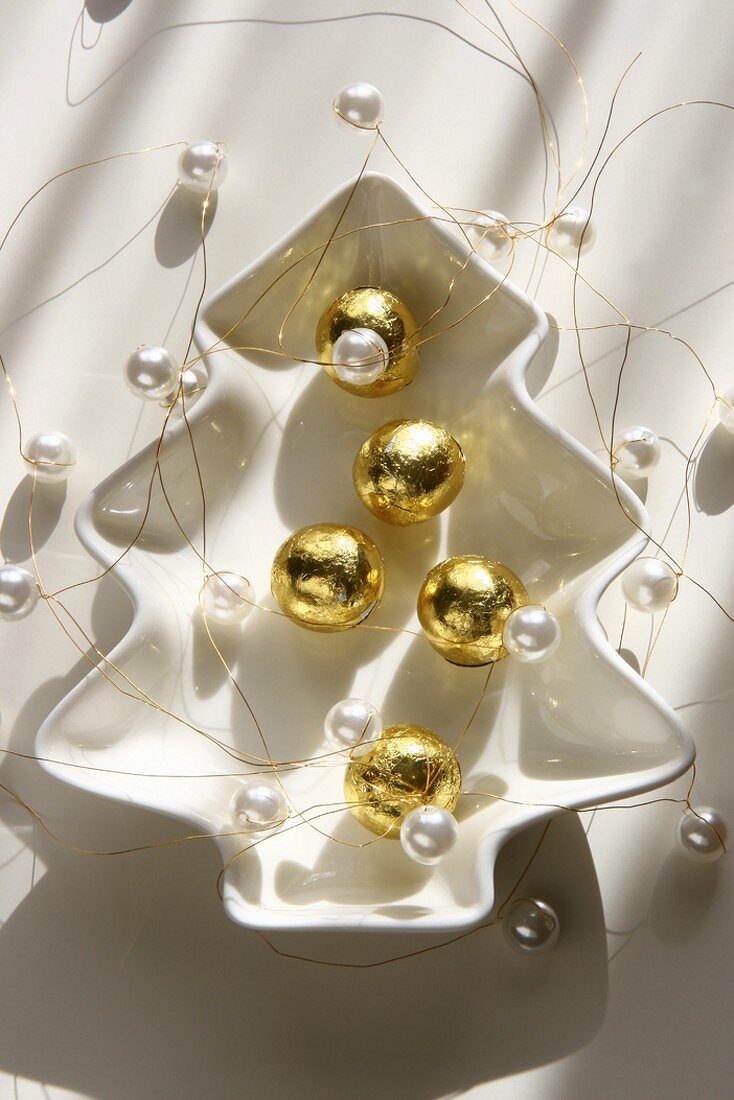 Chocolate balls wrapped in gold foil, strings of pearls