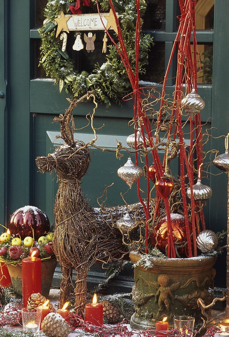 Weihnachtsdeko mit Weiden-Rentier und Gestecken vor der Tür