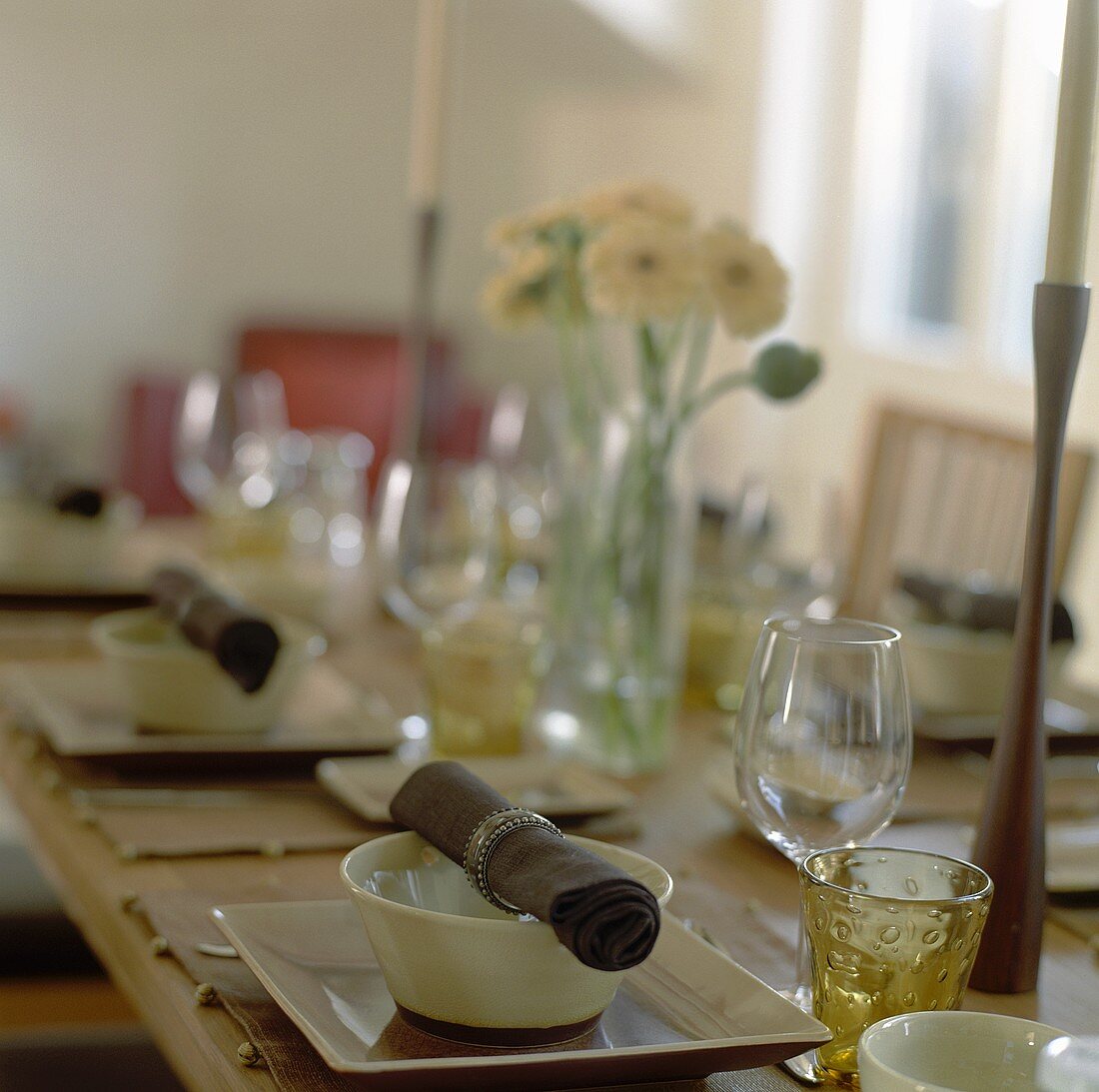Gedeckter Tisch mit Stoffservietten, Kerzen und Blumen