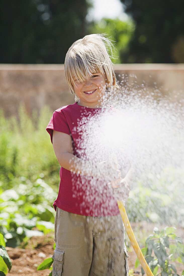 A boy spraying water from a garden hose