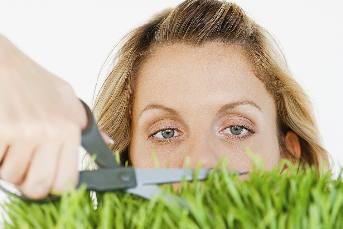 Frau schneidet mit einer Schere den Rasen