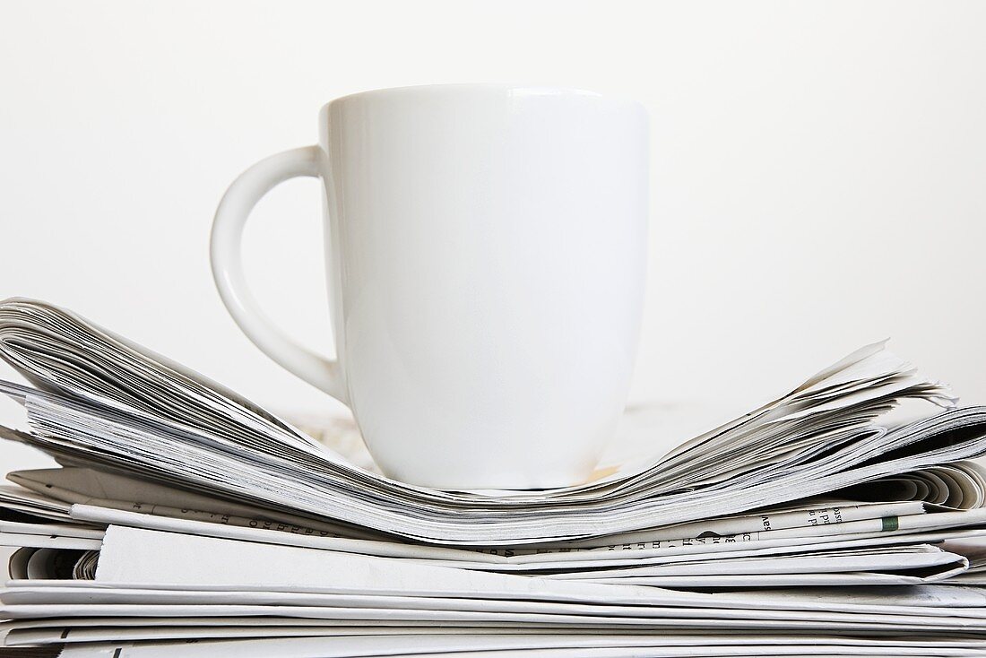 A cup on stack of newspapers