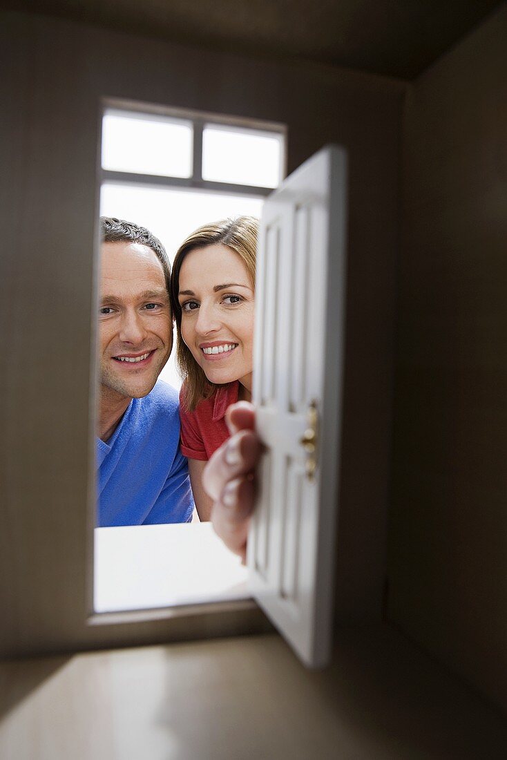 A young couple looking through the door of a model house