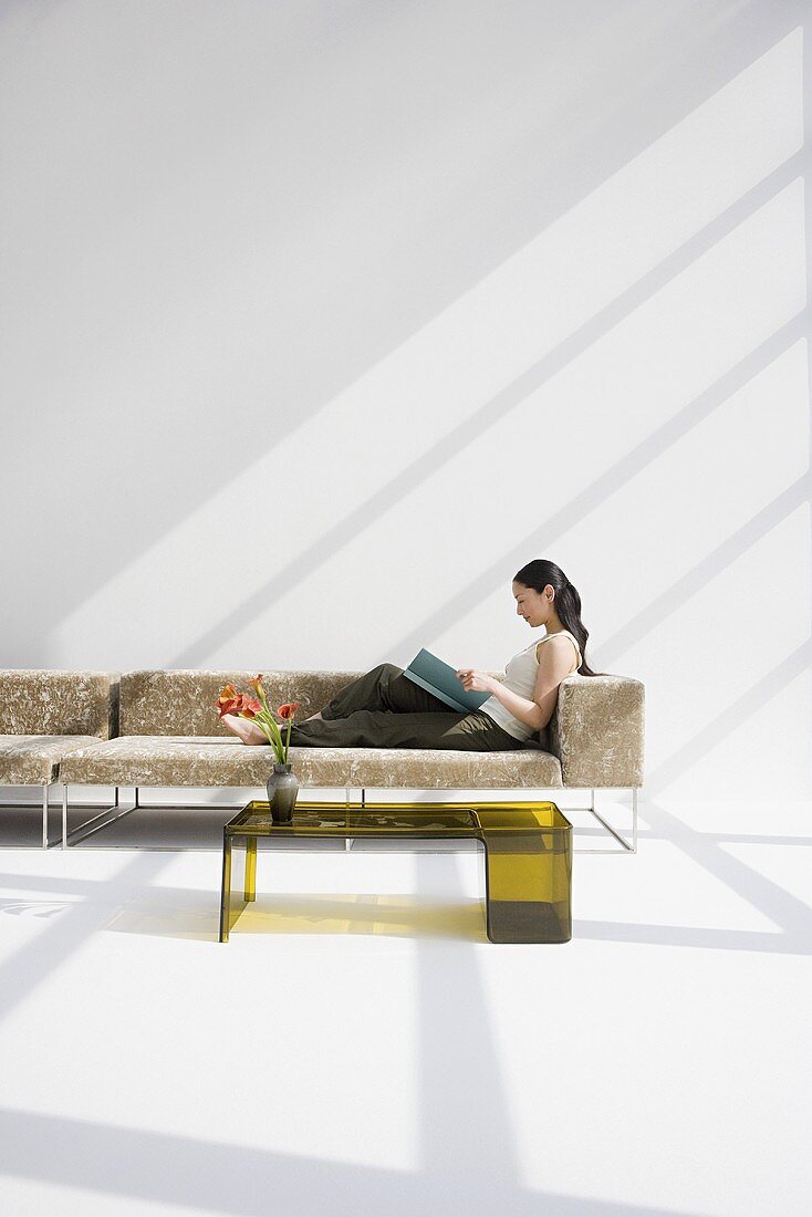 Lesende Frau auf Sofa eines modernen Wohnzimmers