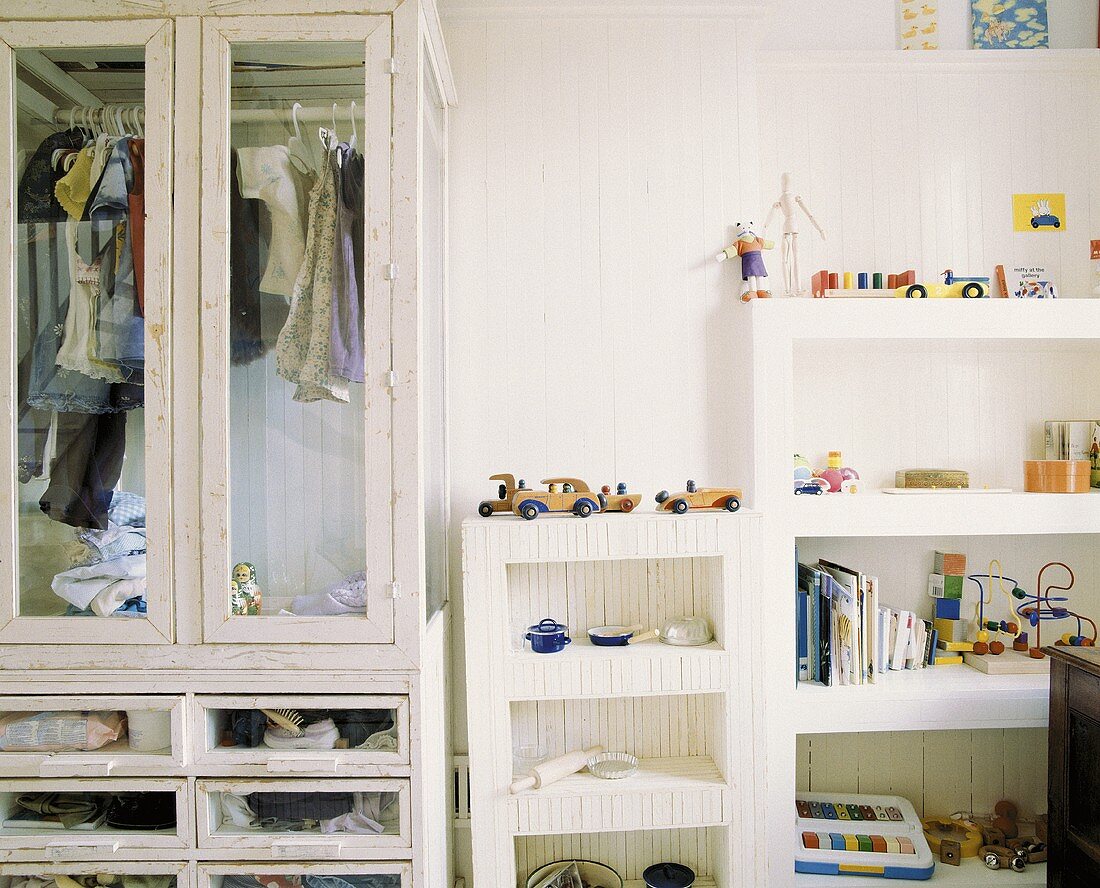 Kinderzimmer mit Vitrinenschrank im Shabby Stil und einem Wandregal mit Spielzeug und Büchern