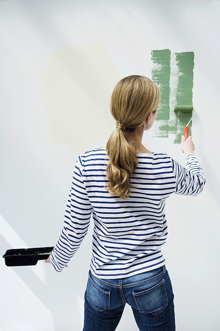 A woman painting a wall