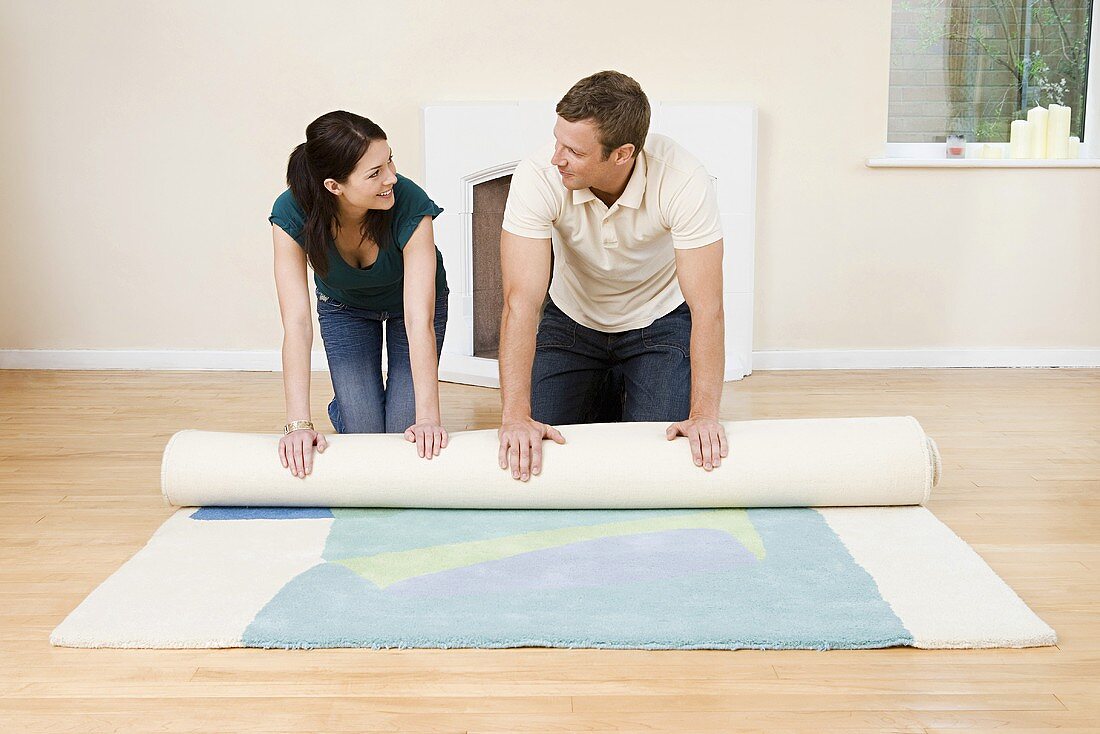 A couple rolling out a rug
