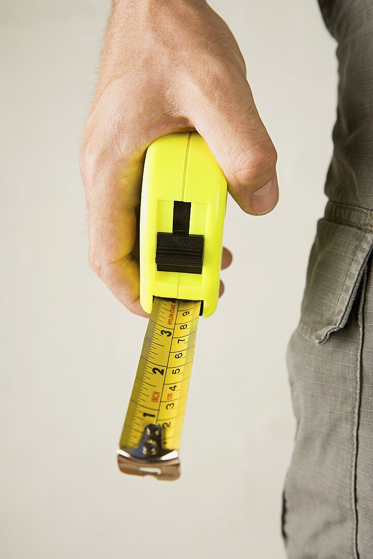 A hand holding a tape measure