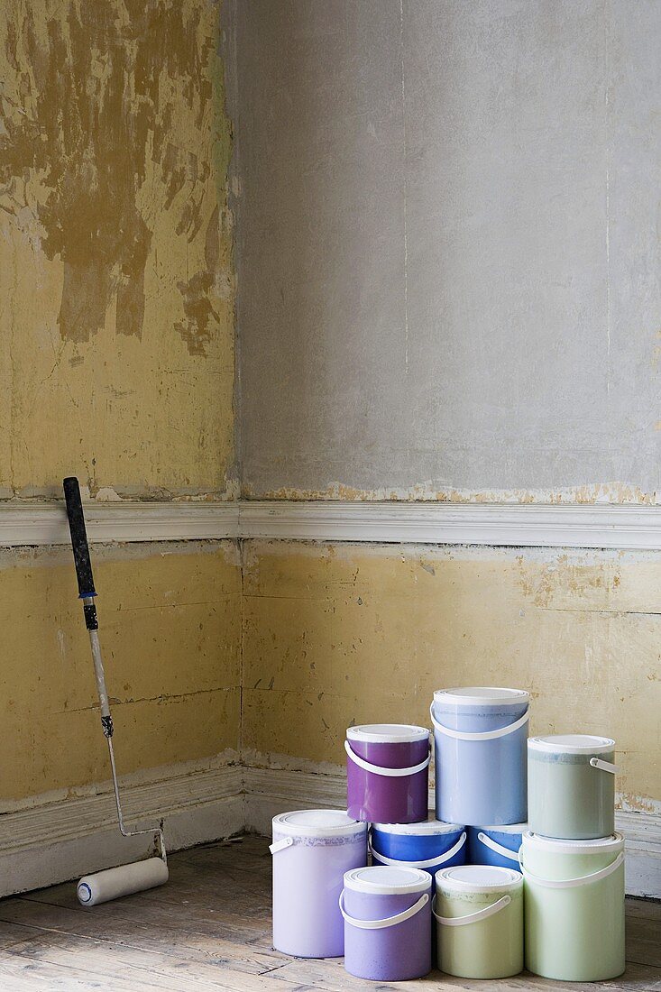 A paint roller and pots of paint in a room
