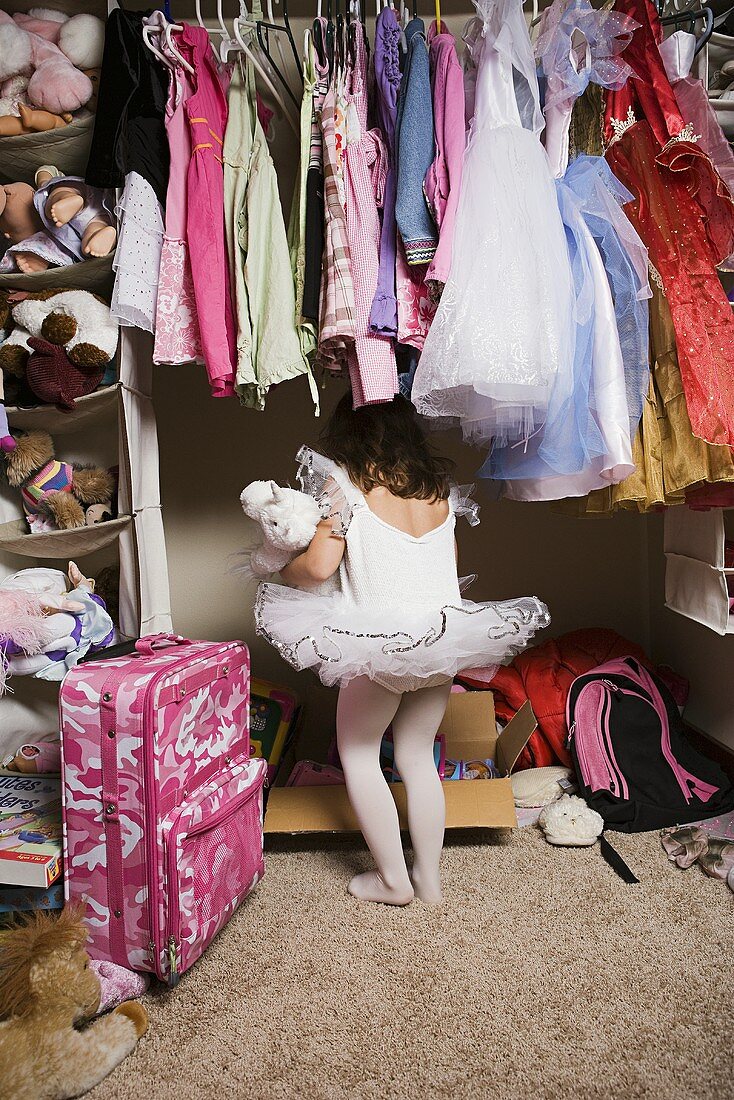 Mädchen in Ballettröckchen sucht im Kleiderschrank