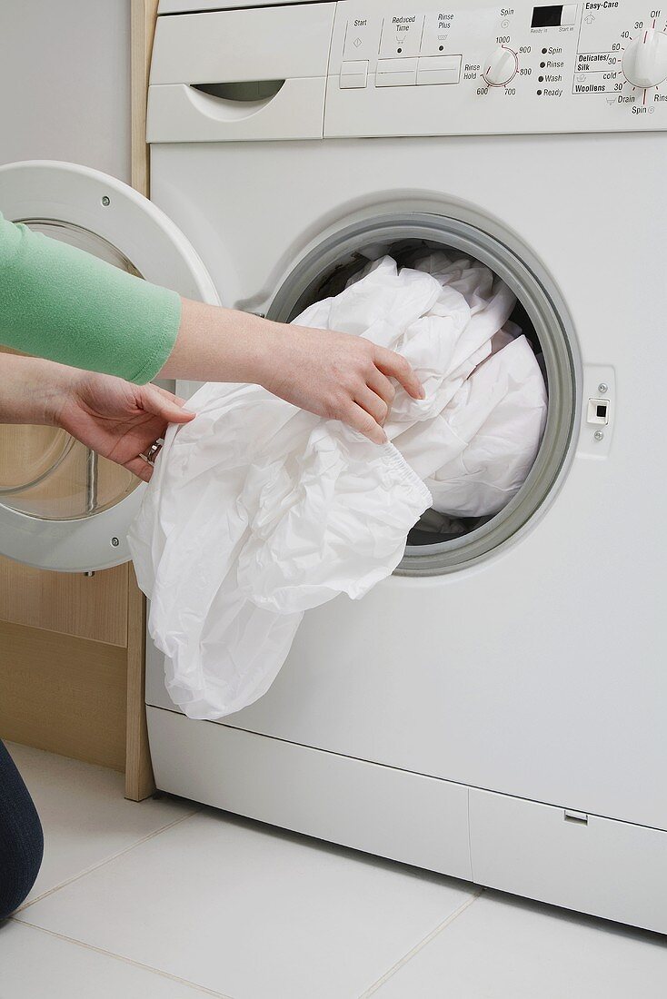 Frau zieht Wäsche aus Waschmaschine