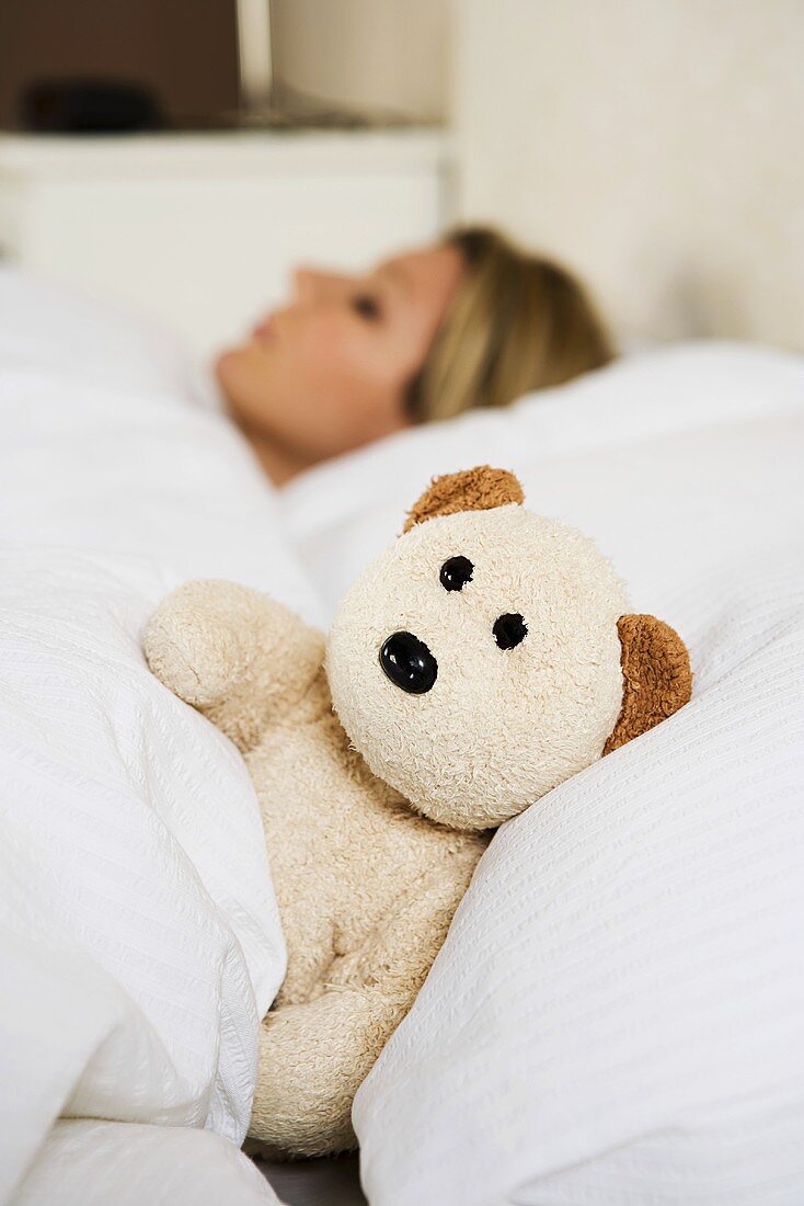Frau im Bett mit Teddybär