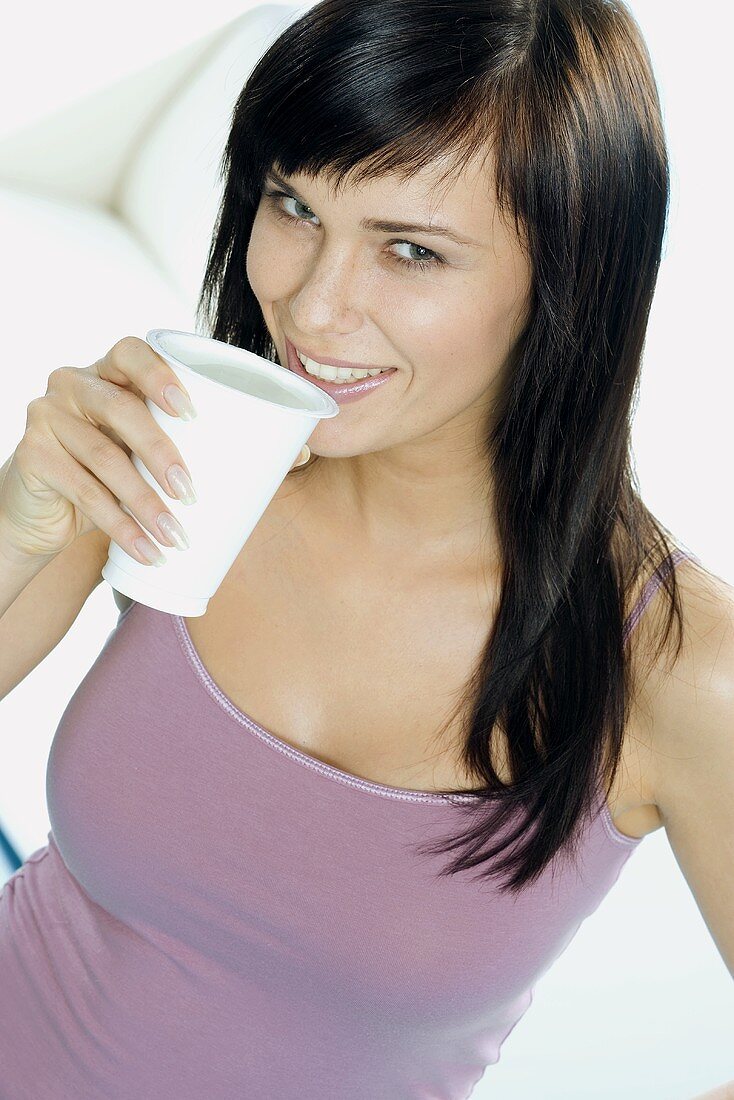 Junge Frau mit einem Becher Trinkjoghurt