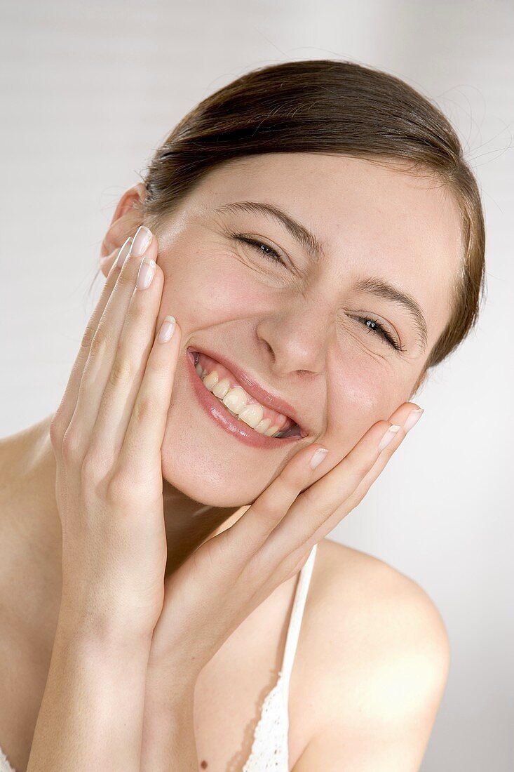 Smiling young woman with her hands on her cheeks
