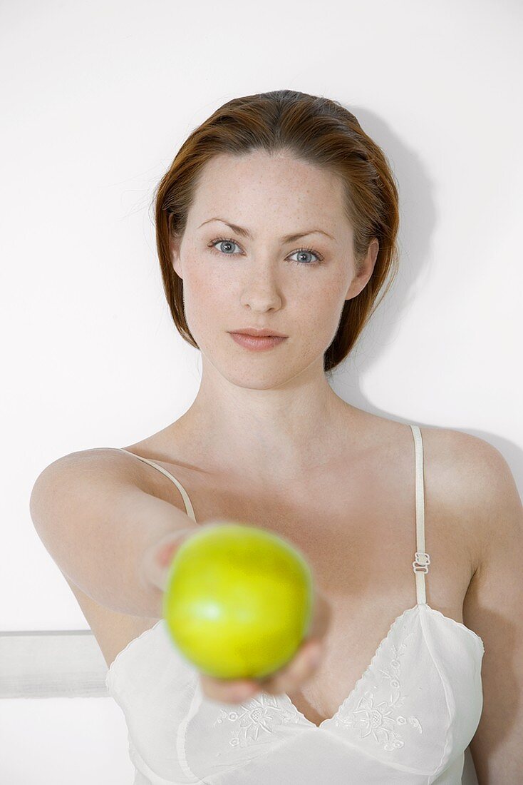 Junge Frau hält einen grünen Apfel in der Hand