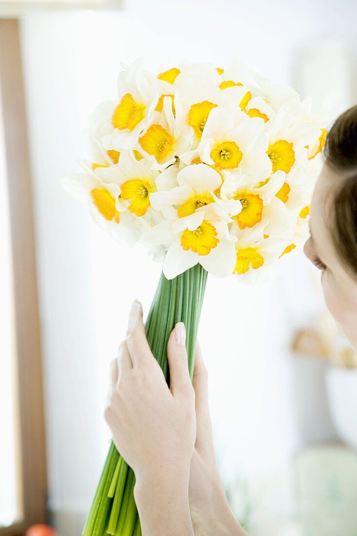 Woman holding white narcissi in her hands