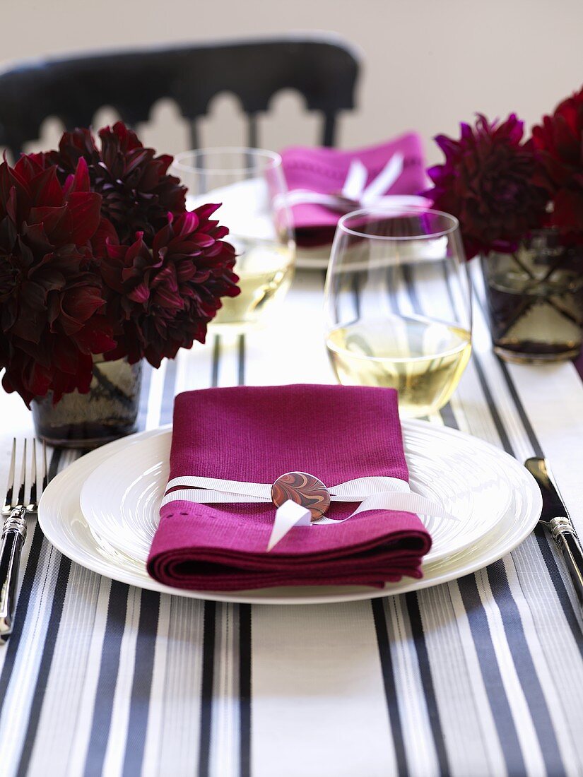 A place setting with a white plate and a pink napkin