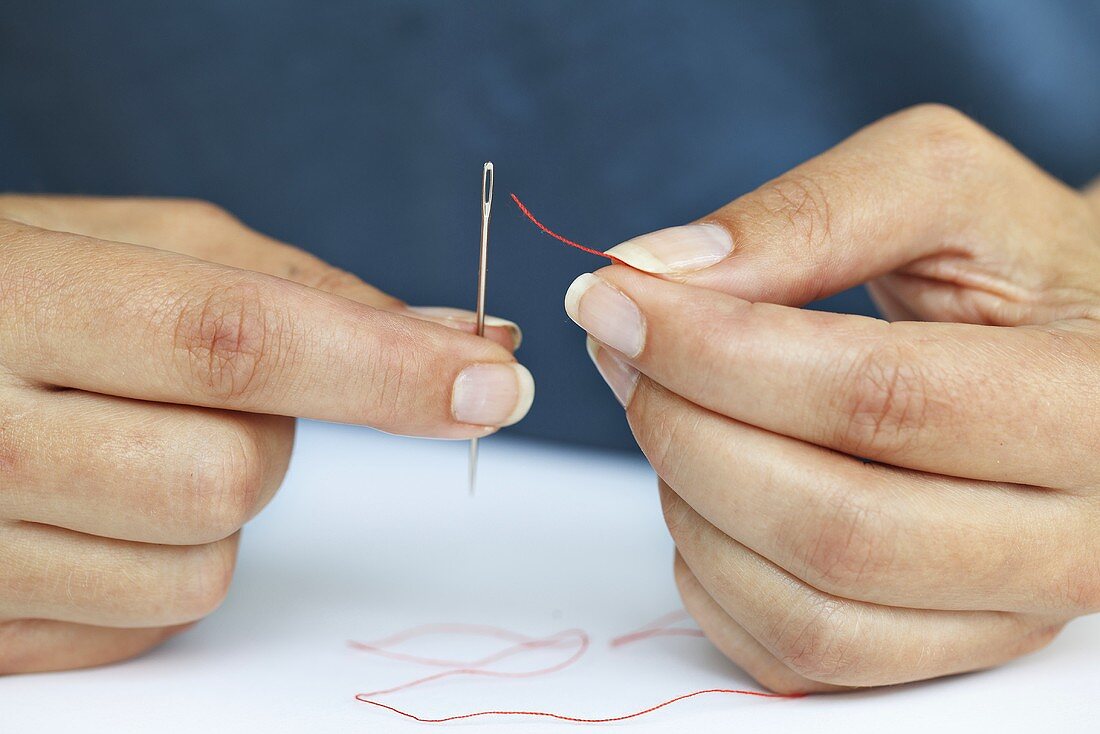 Woman threading a sewing needle