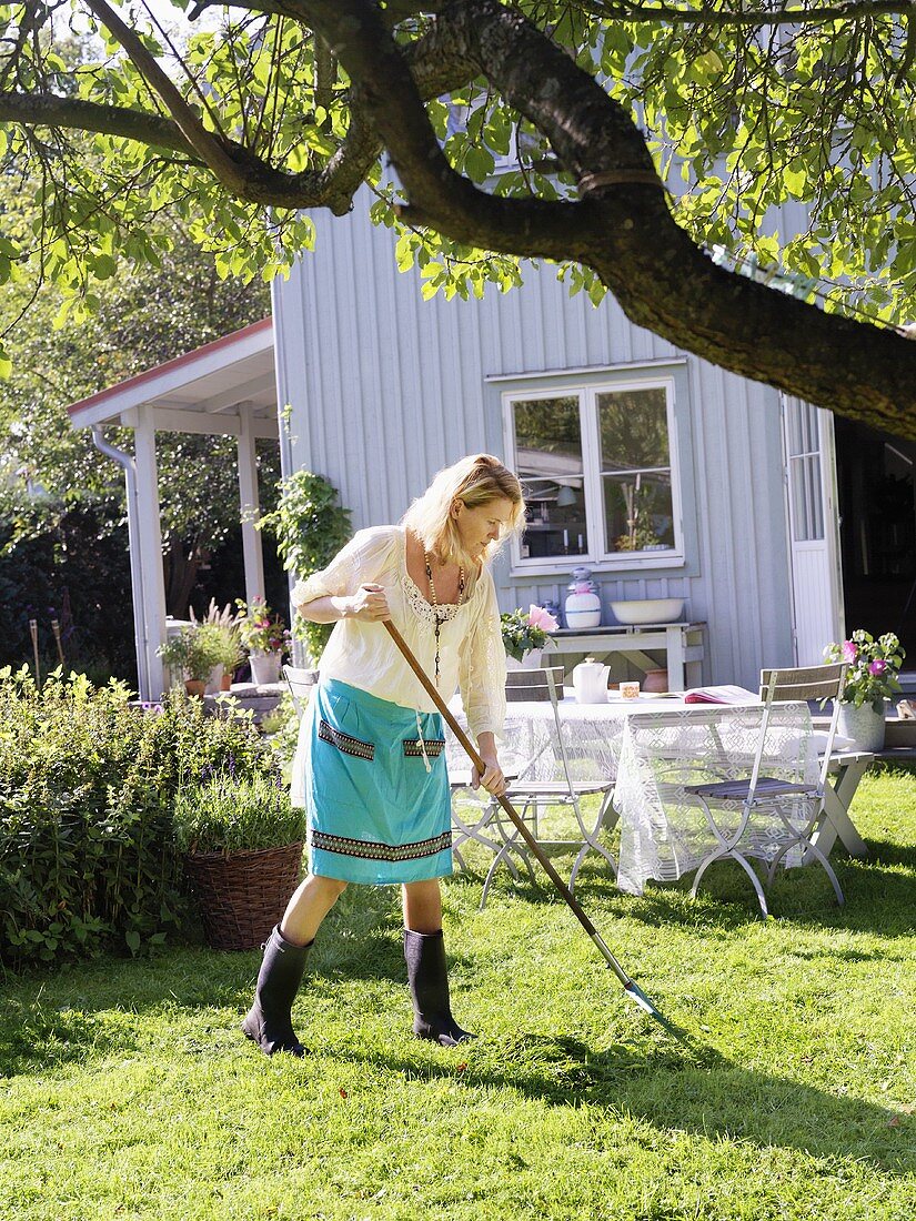 Frau hakt im Garten Gras zusammen